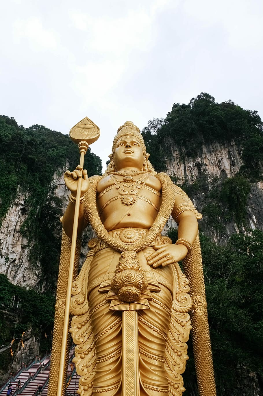 low angle photograph of Buddha statue near mountain cliff under cloudy sky, gold-colored sculpture on mountain HD wallpaper