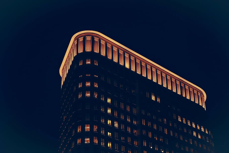 high rise building with lights turned on, roof, illuminated, construction