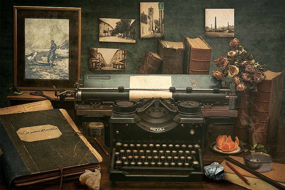 black Royal typewriter beside black book on table, former, antique