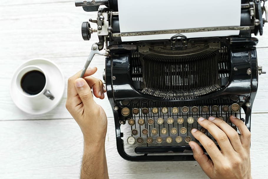 person using typewriter with coffee on the side, technology, equipment