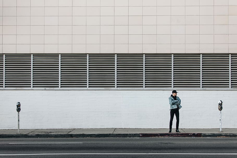 man standing on the sidewalk, man standing on street beside concrete wall HD wallpaper