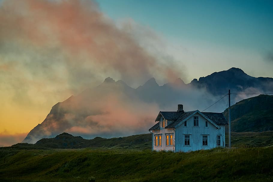 white and gray house on green grass under golden hour, white wooden house and foggy mountain