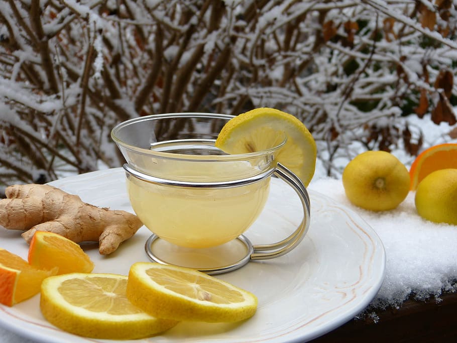 clear glass teacup with yellow substance on top of white plate HD wallpaper