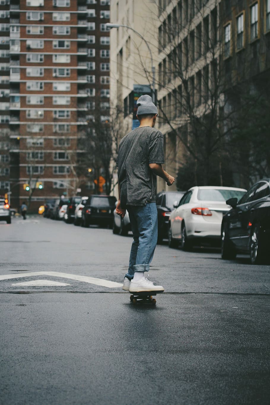 man riding skateboard near high rise building, man riding on skateboard
