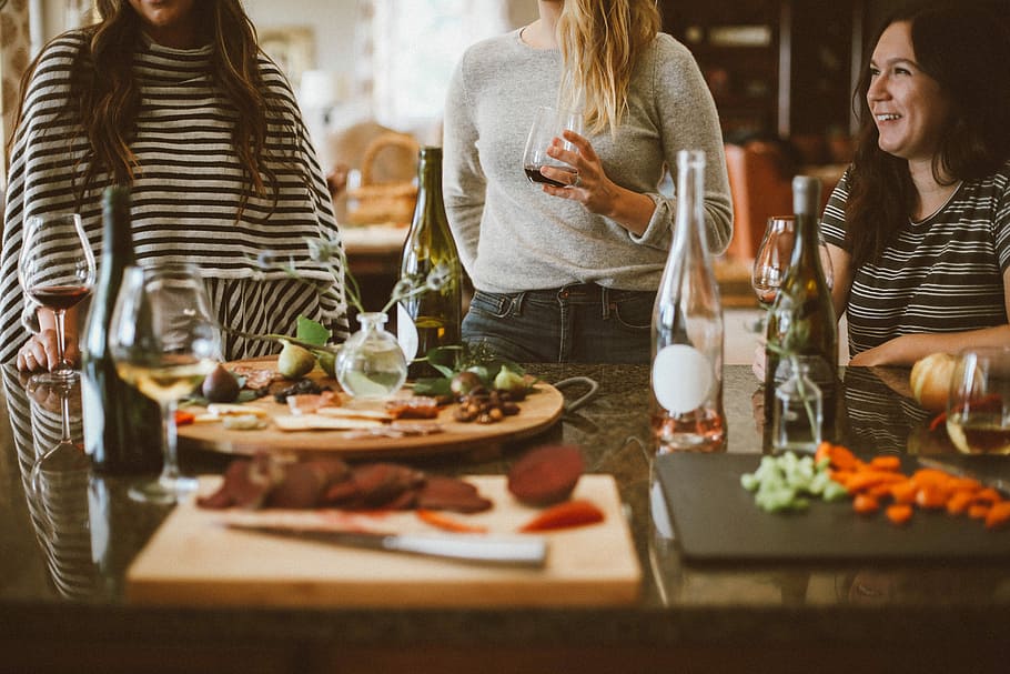 two woman standing beside woman sitting in front of table, people drinking wine HD wallpaper