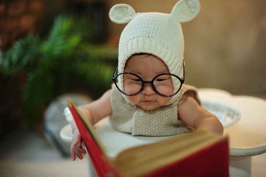 baby wearing gray knitted pram suit and eyeglasses holding book HD wallpaper