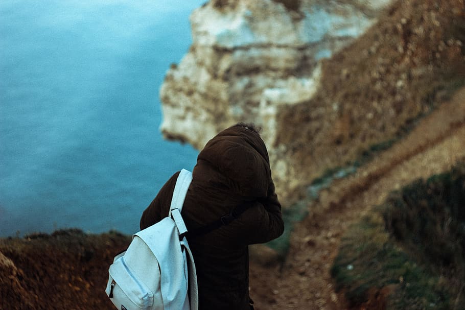 person with blue backpack near body of water, person in black hoodie with backpack walking in pathway near body of water during daytime, HD wallpaper