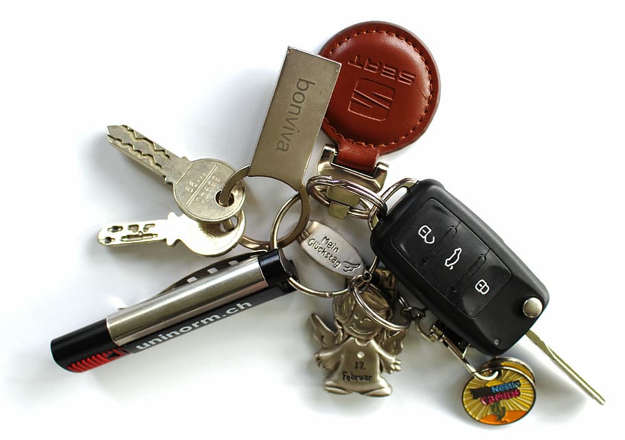 gray and black key with keychain on white surface, car keys, door key