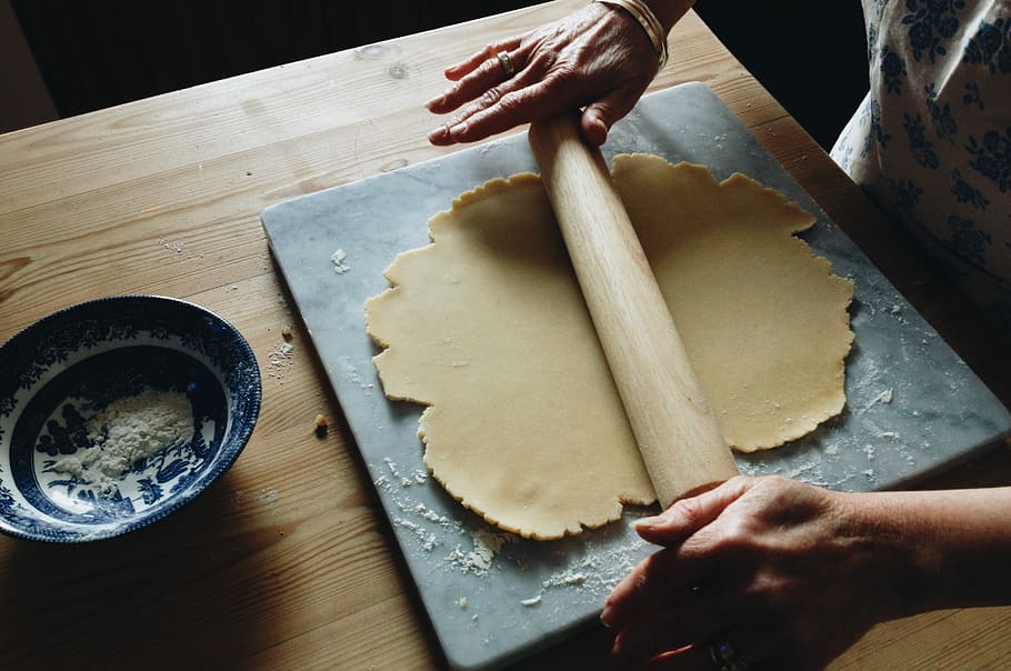 man holding brown rolling pin, person holding roller pin while rolling dough HD wallpaper