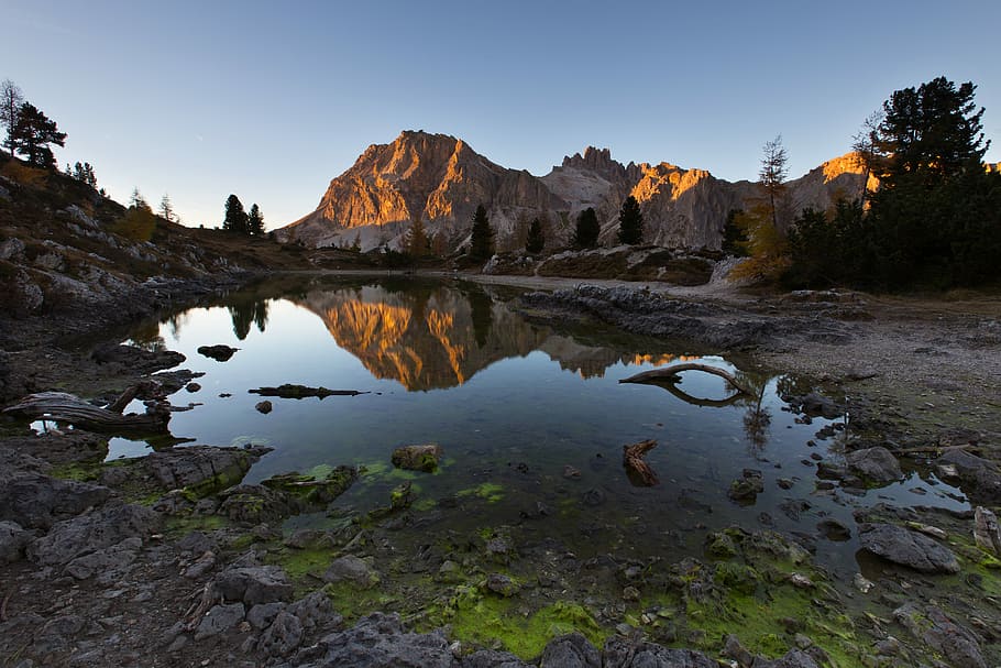 water mirror reflection of mountain during golden hour, river and brown rock mountain under blue sky during daytime HD wallpaper
