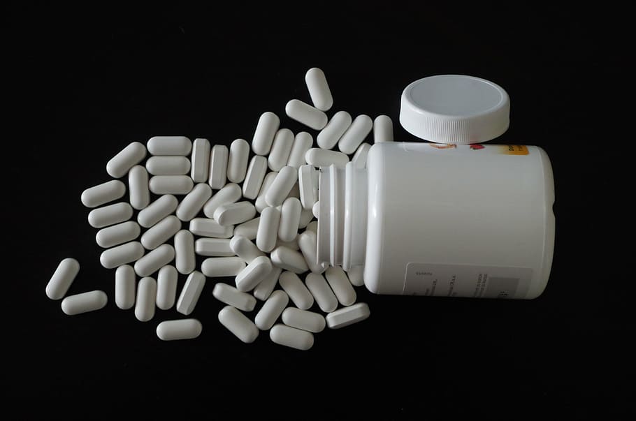 medication capsules beside container, diet pills, pharmacy, sick