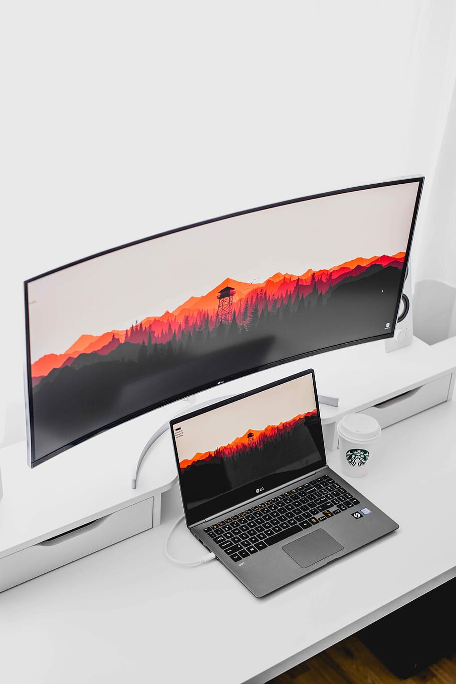 laptop computer beside curved monitor, curved monitor, laptop computer, and Starbucks cup on white wooden table