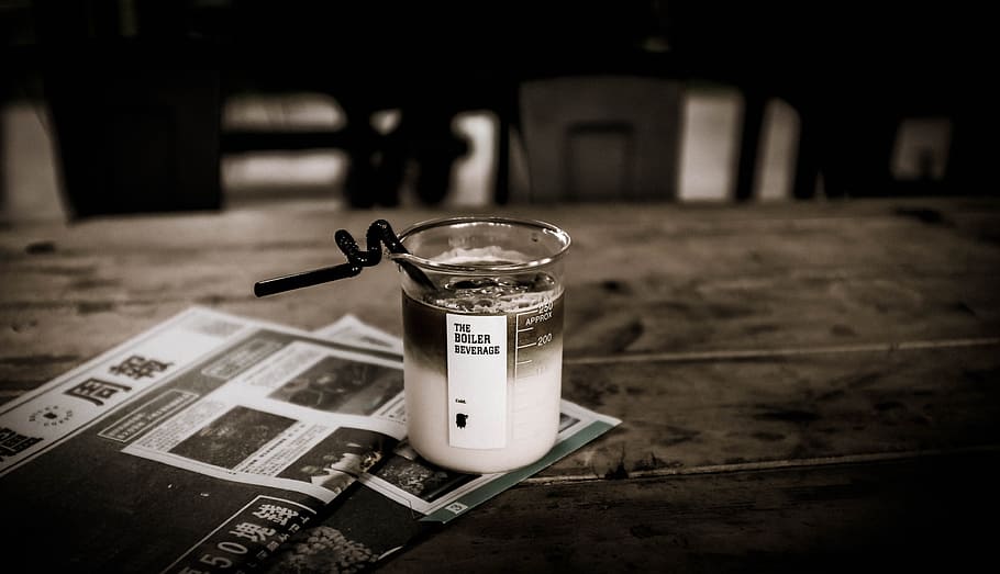 shallow focus photography of smoothie in glass on table, gray scale photography of clear drinking glass with liquid on printed paper HD wallpaper