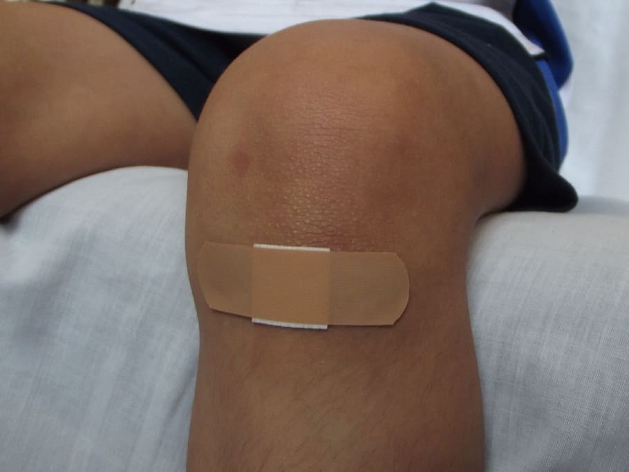 person wearing black shorts with band aid, wound, wounds, wounded