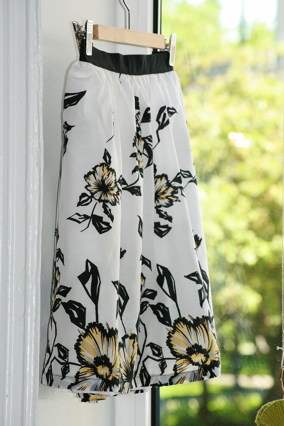 shallow focus photo of white, black, and yellow floral skirt hanging