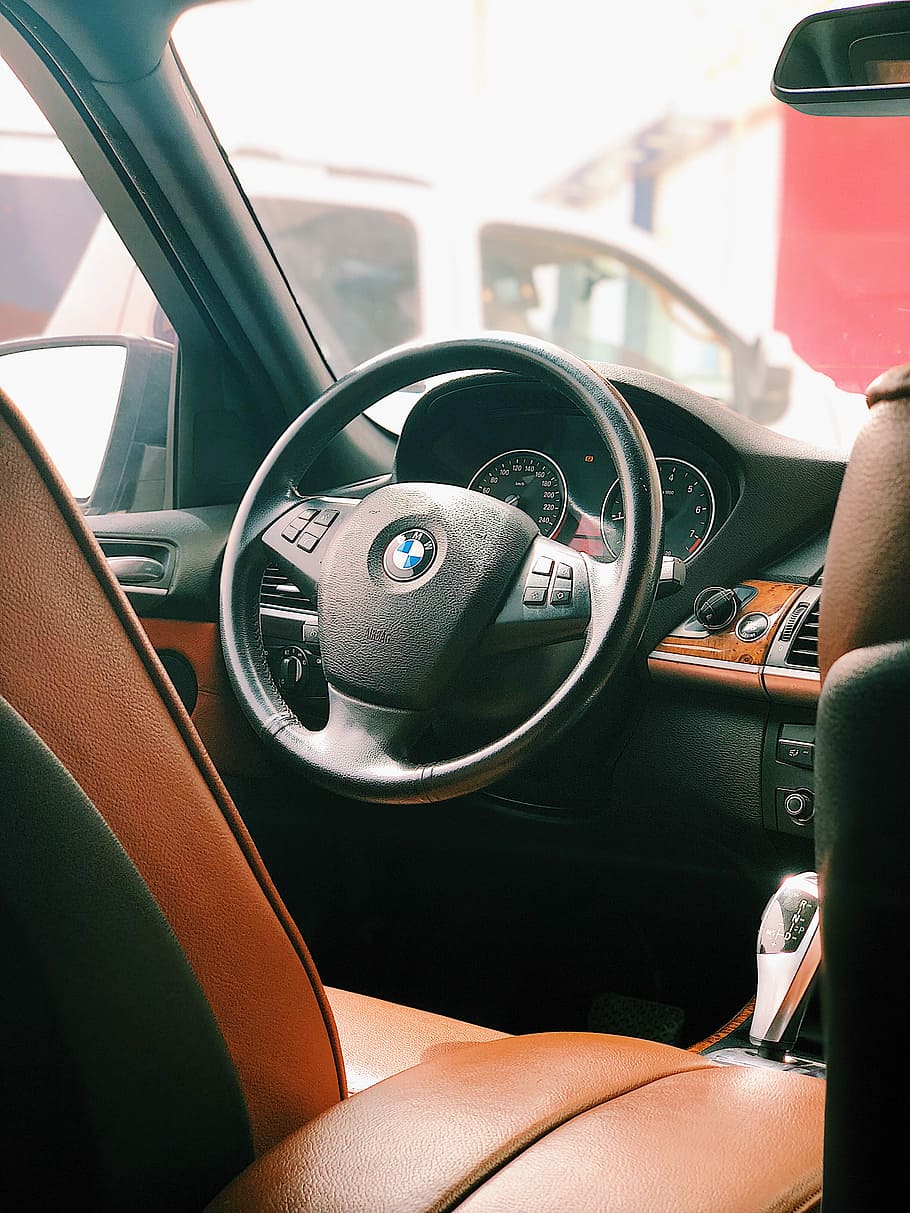 BMW vehicle interior near white van at daytime, black BMW car steering wheel