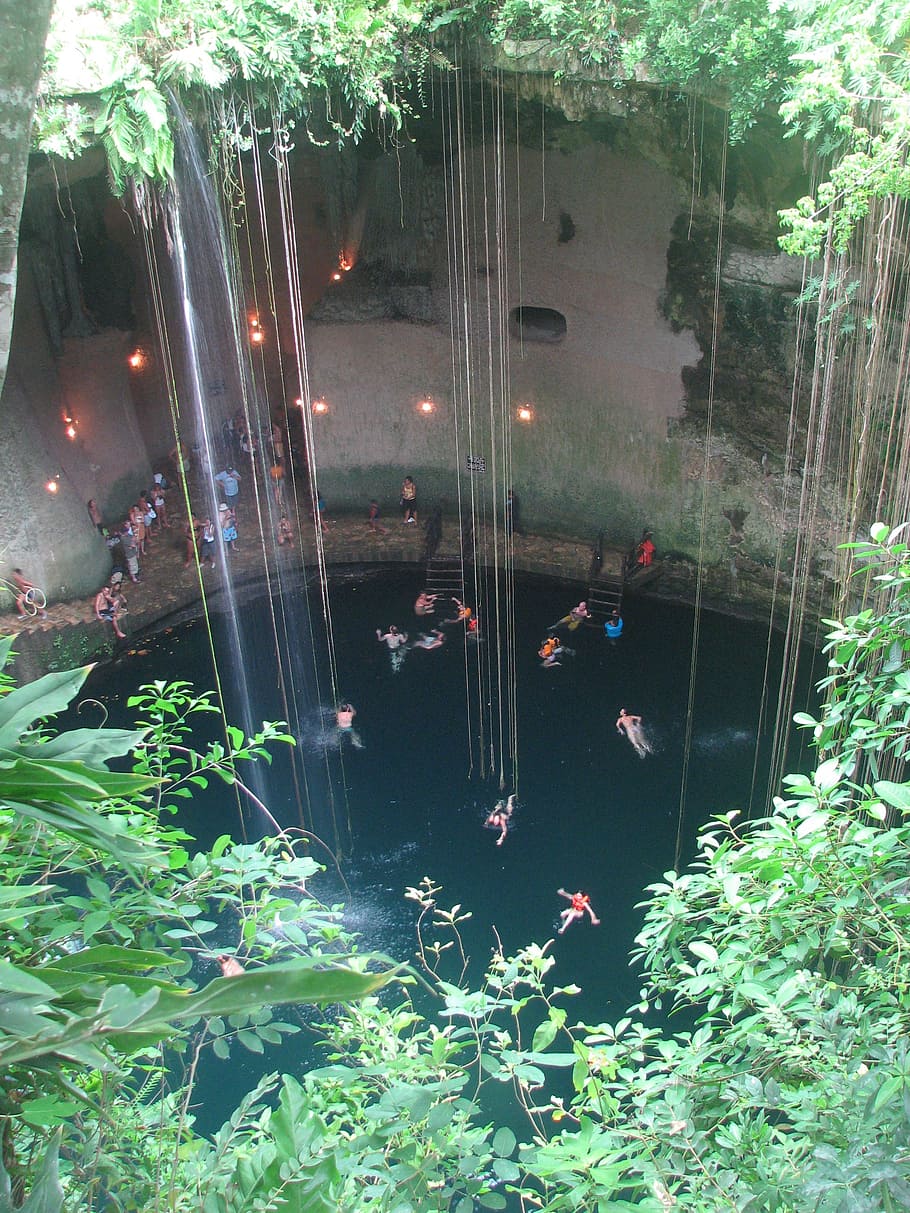 people swimming on body of water near cliff, cenote, cave, yucatan