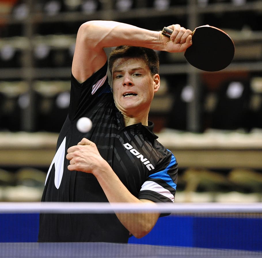 selective focus photography of man playing table tennis, ping pong