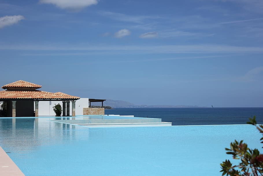 landscape photography of blue swimming pool with over-view of sea at daytime HD wallpaper