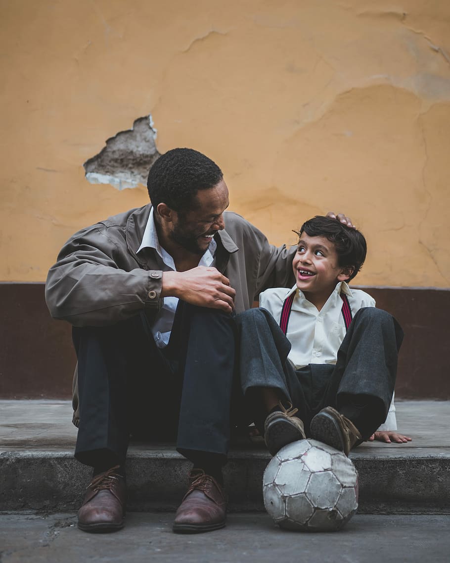man holding boy's head, man and boy standing beside each other on sidewalk while talking and laughing together HD wallpaper