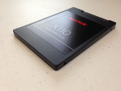 black SanDisk X110 solid state drive on top of white countertop HD wallpaper