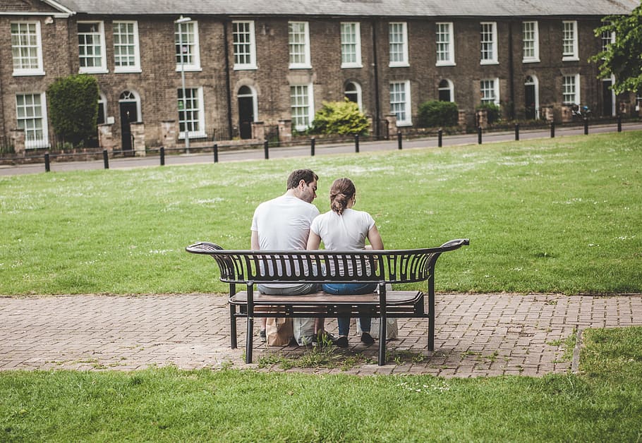 man and woman sitting on bench, man and woman sitting on bench in front of building during daytime HD wallpaper