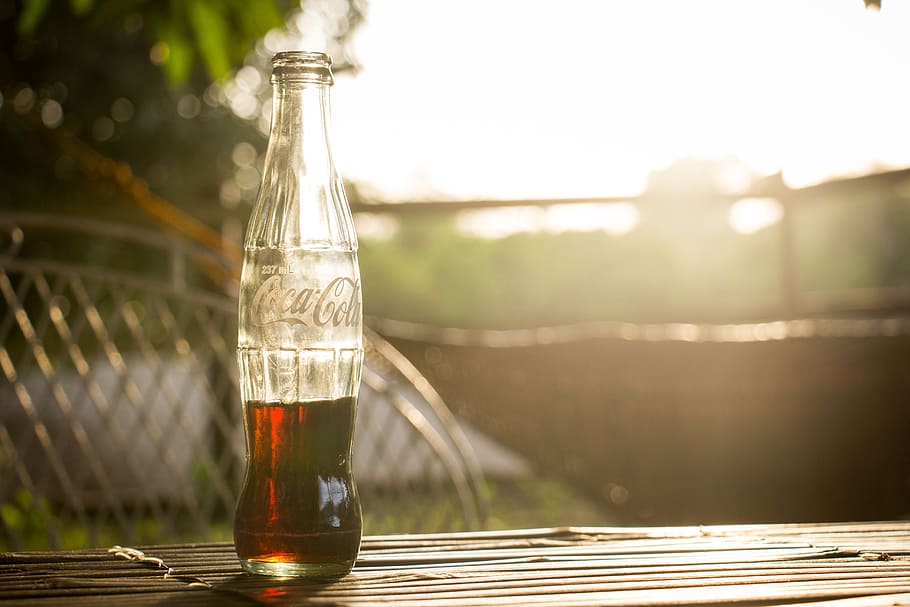 selective photo of a Coca-Cola bottle, half-filled Coca-Cola glass bottle