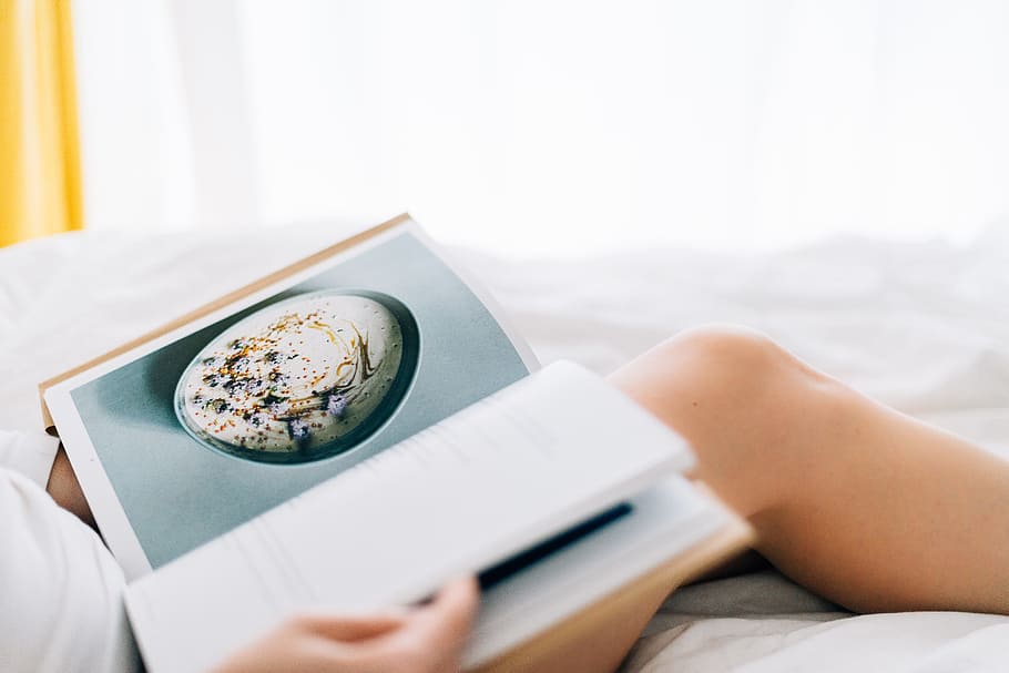 In search for healthy treats, person reading book on white bed HD wallpaper