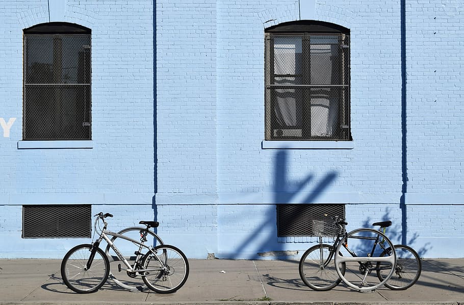 two bicycles parked in front of blue building, two black bikes outside building HD wallpaper