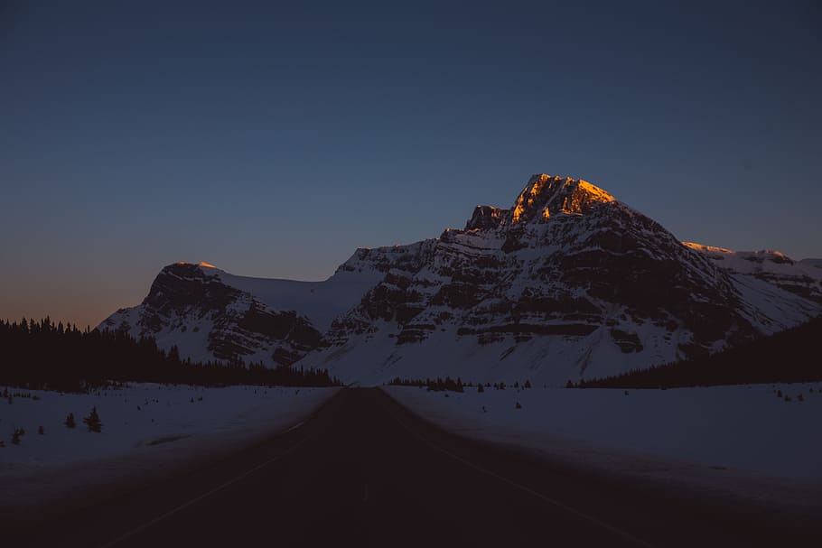 snow capped mountain, highway through snow-covered mountain during daytime HD wallpaper