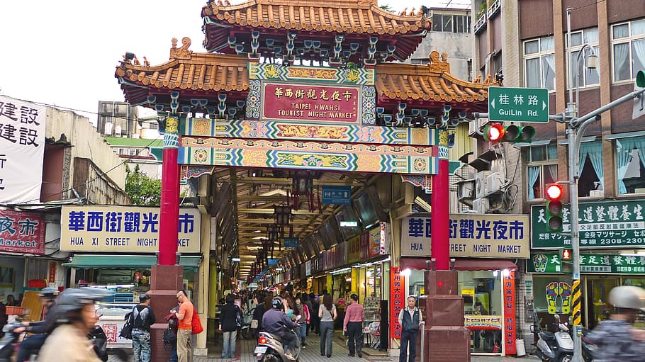 brown and red Chinese arch surrounded by people during daytime