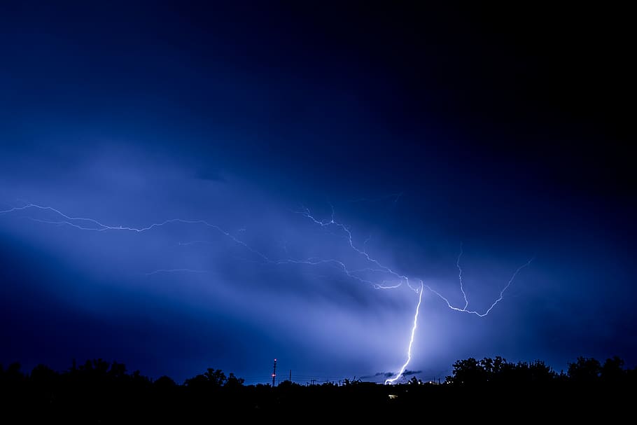 thunder light strike on forest, photo of blue lightning at night time