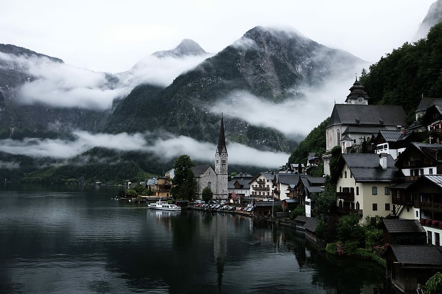 village near lake surrounded by fogs, houses near body of water and mountain HD wallpaper