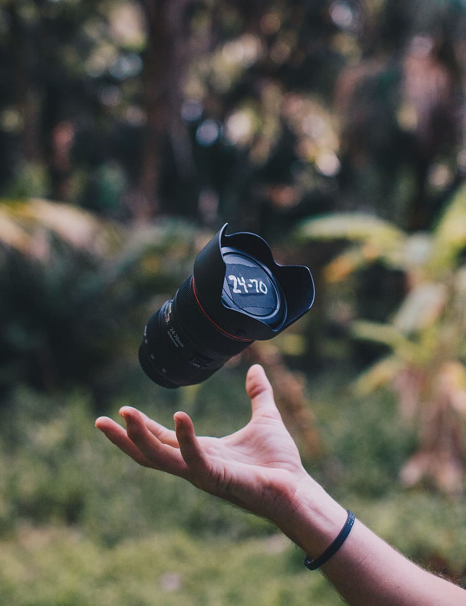 shallow focus photo of black DSLR camera lens, person catching black DSLR camera lens during daytime photography HD wallpaper