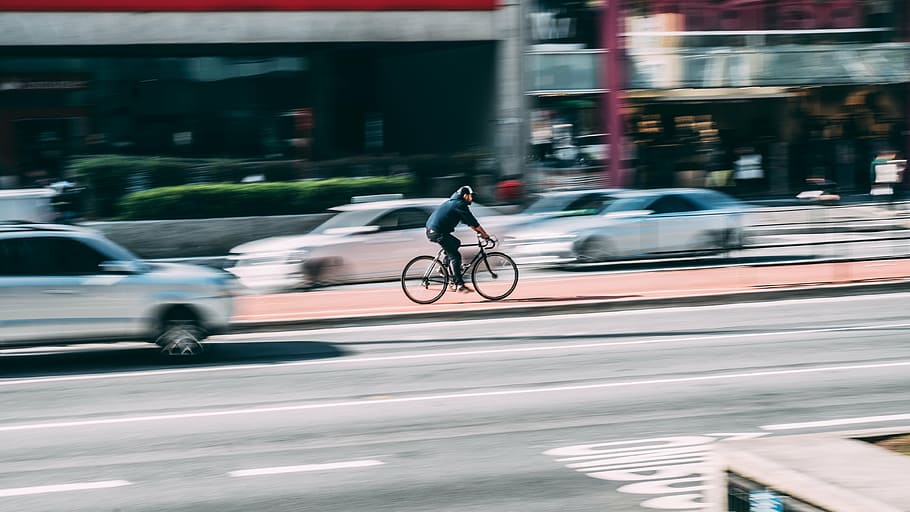 time lapse photography of man riding road bike near vehicle passing by at daytime HD wallpaper