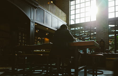 man seating on bar stool, person sitting on black stool indoor during daytime HD wallpaper