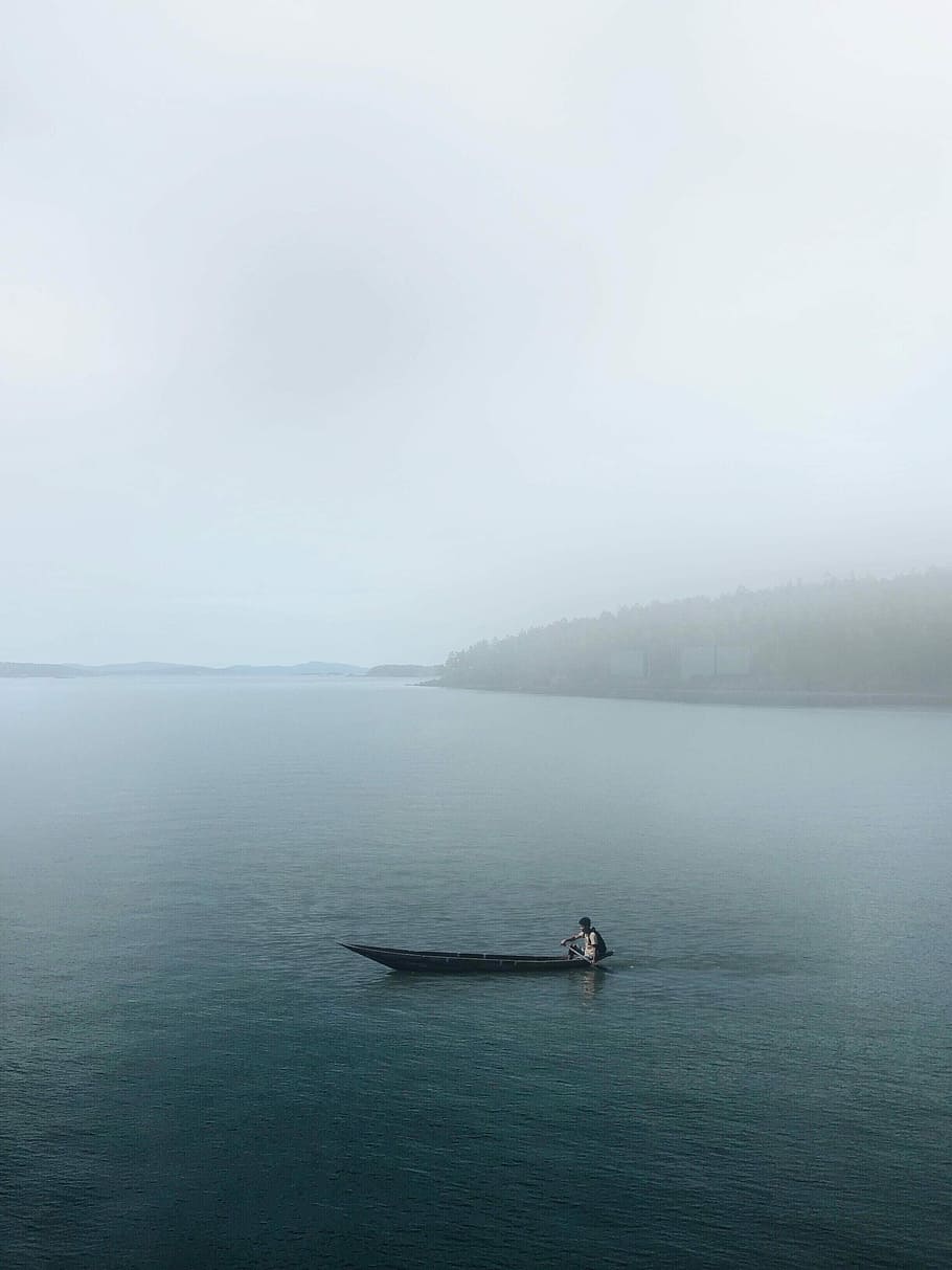photo of person on canoe, man riding boat on sea near mountain HD wallpaper