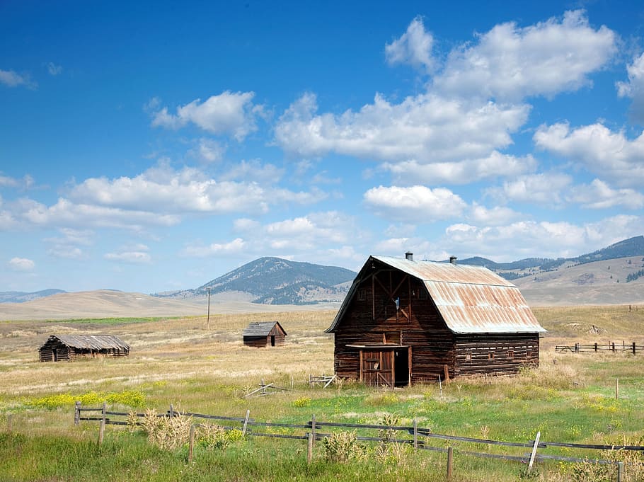 photo of three brown wooden barn in farm white nimbus clouds
