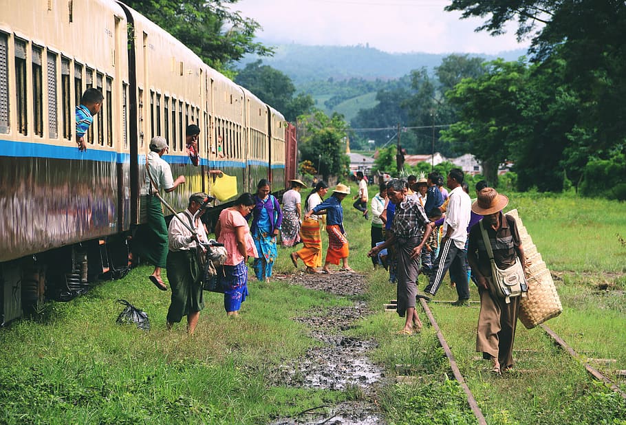 group of people standing outside train, people getting out of train and walking on green grass field during daytime
