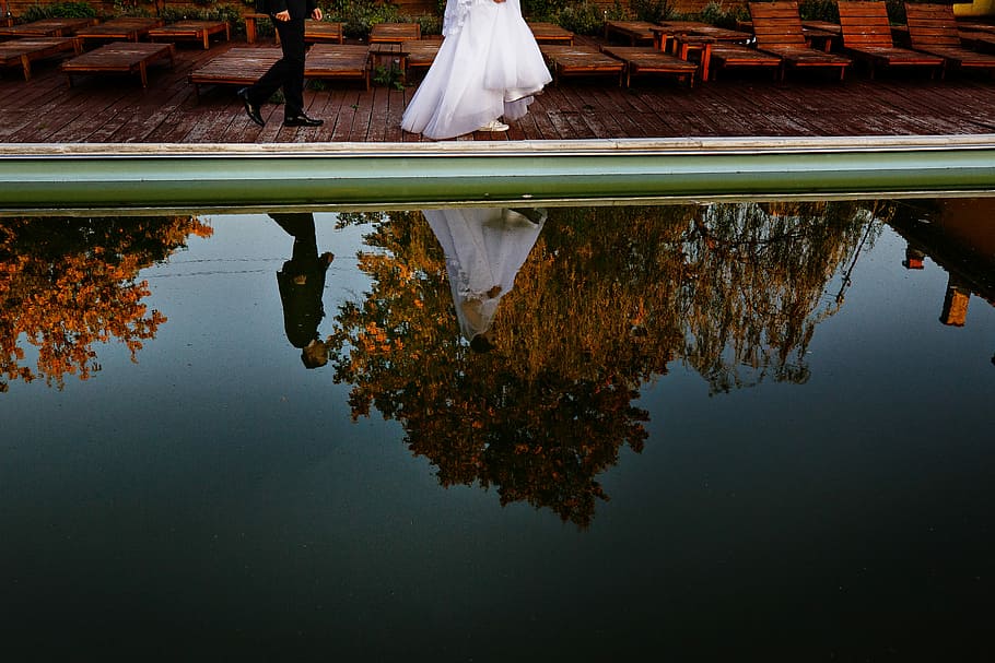 woman and man walking towards dock beside body of water, groom and bride walking beside pool during daytime HD wallpaper