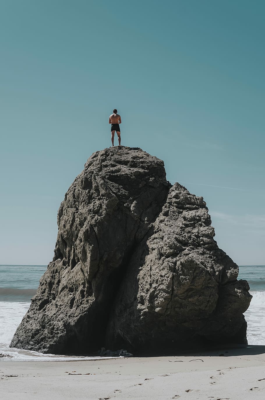 person standing at rock formation, man standing on boulder on beach shore HD wallpaper