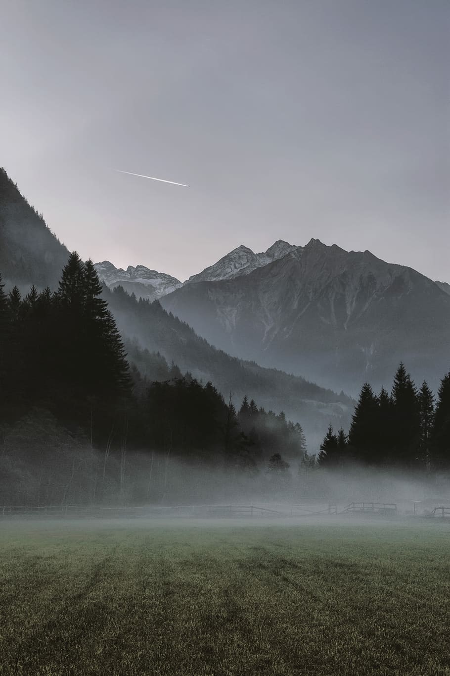 landscape photo of mountains covered by fogs and view of contrail, green field around mountains HD wallpaper