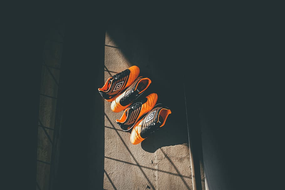 two pairs orange-and-black Umbro shoes, two pairs of orange Umbro cleats