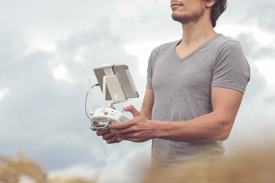 man holding white and gray drone controller, man holding white quadcopter controller HD wallpaper