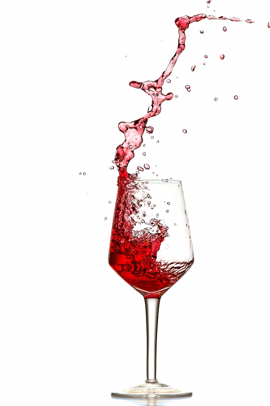 pouring of red wine in clear long stem wine glass, splash, pour out