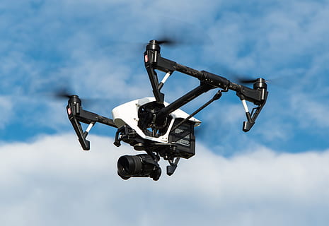 black and white quadcopter drone flying under cloudy sky during daytime HD wallpaper