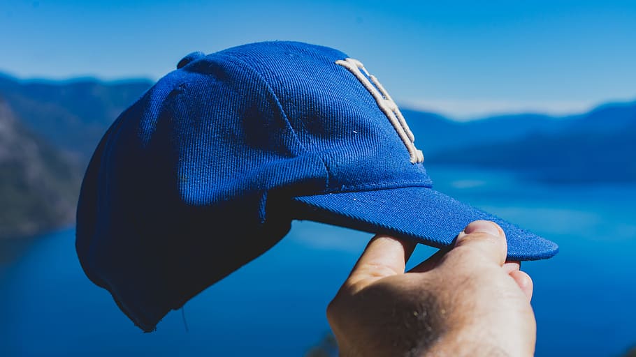 person holding blue fitted cap, hat, hand, one Person, outdoors HD wallpaper