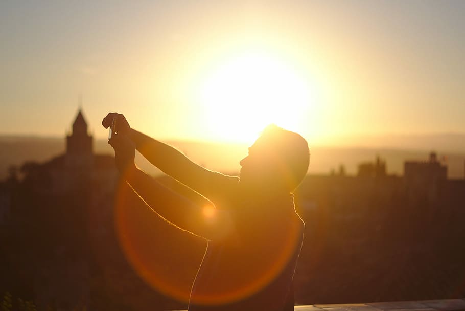 man raising hands under sunset, golden hour photography of man standing on top of a building HD wallpaper
