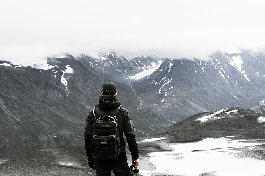 man standing at mountian, man wearing black backpack, mountain