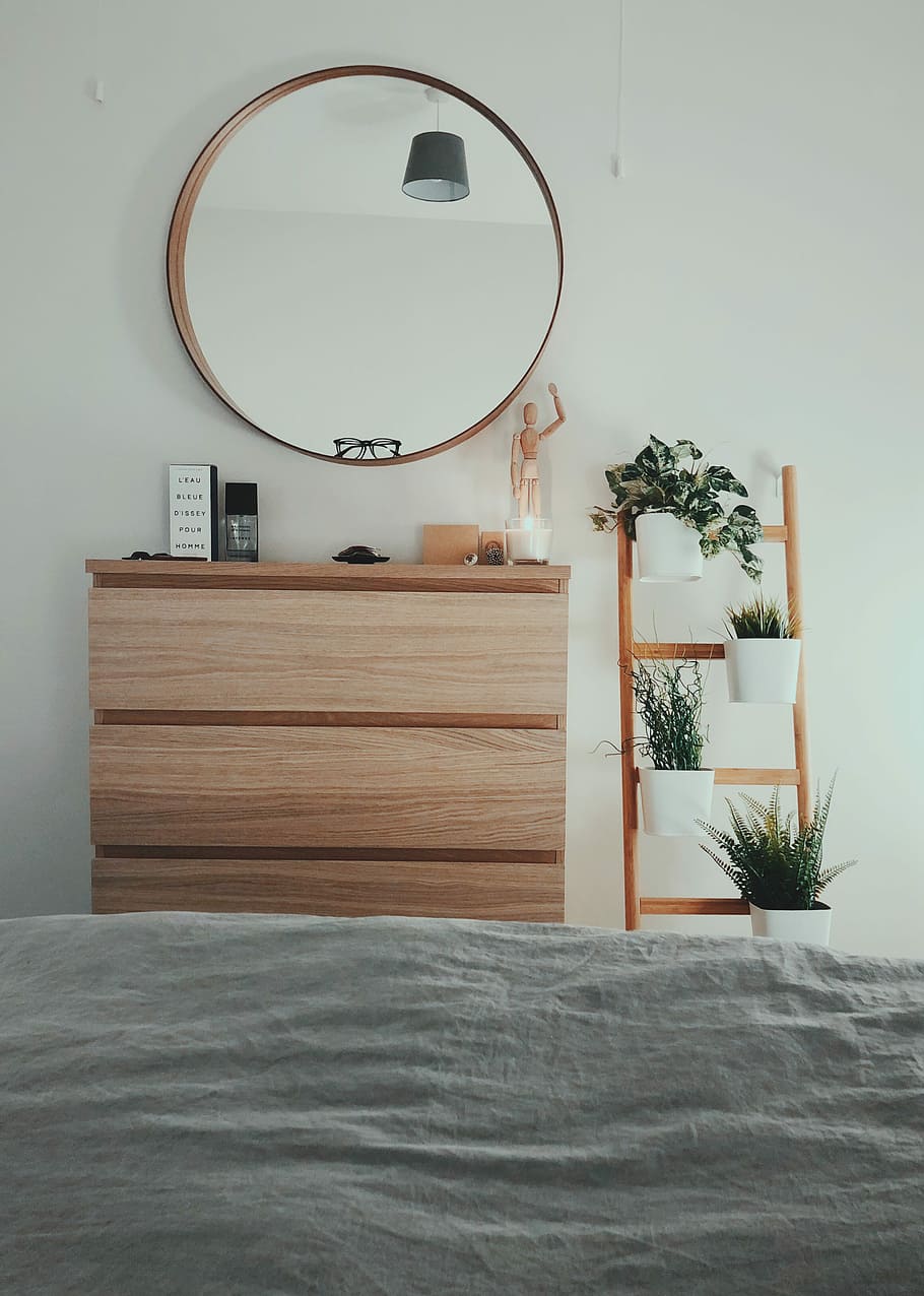 brown wooden 3-drawer chest with round brown wooden framed mirror in front of bed inside room, brown wooden dresser with mirror beside brown wooden flower pot ladder rack, HD wallpaper
